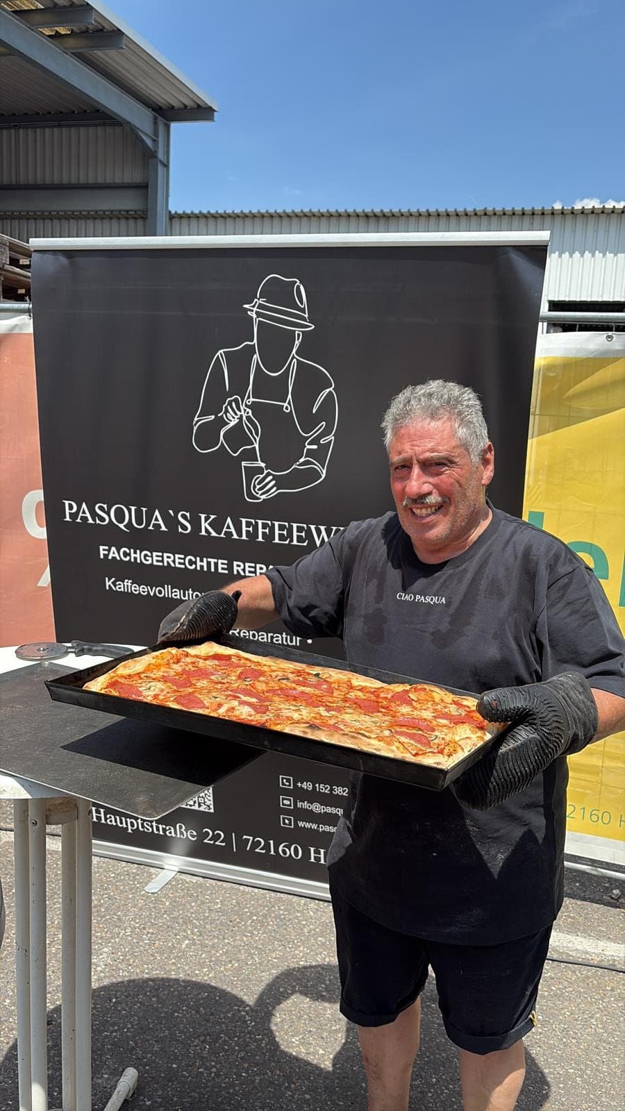 Frisch gebackene Pizza vom Event-Catering wird vor dem Kaffeewerkstatt-Banner präsentiert